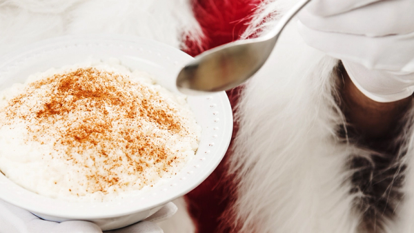 Julenisse som holder en tallerken med julegrøt.