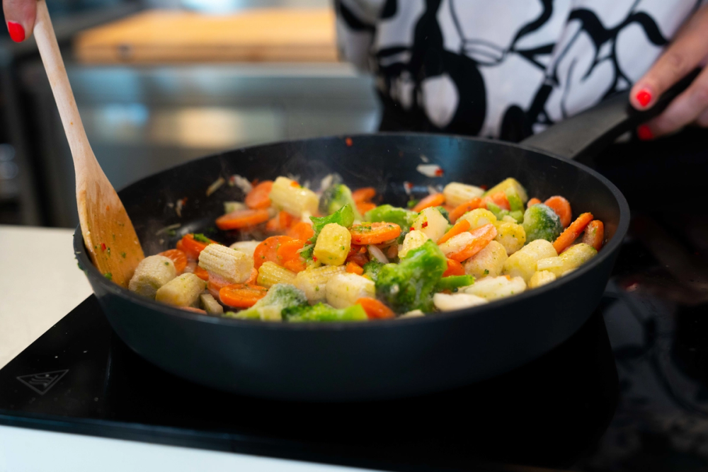 Fryste grønnsaker som varmes opp i en stekepanne.