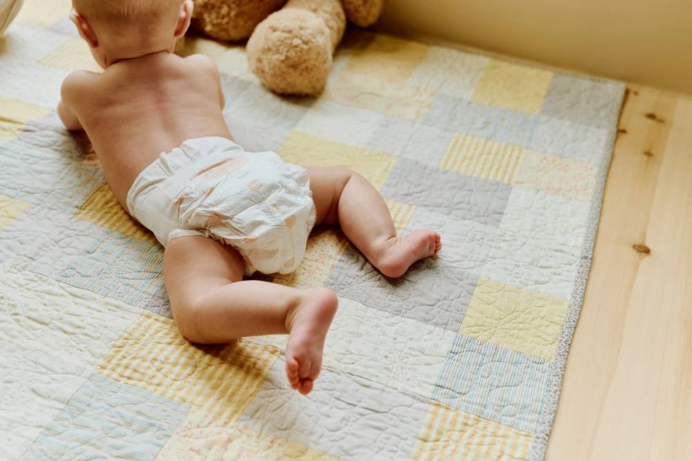 Baby med Vilje bleie på teppe på gulvet.