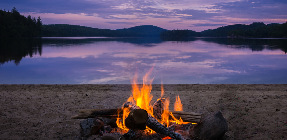 Bål ved vann i skogen.