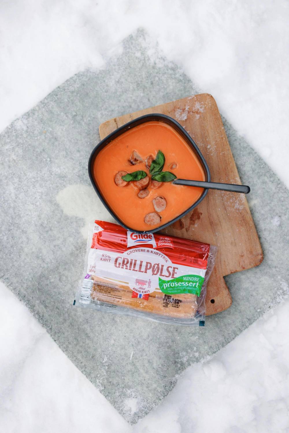 Tomatsuppe med grovere grillpølser på fjøl i snøen.