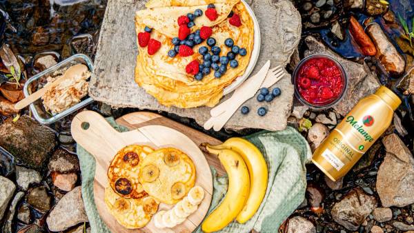 Pannekaker på tur som er toppet med banan, bringebær og blåbær.