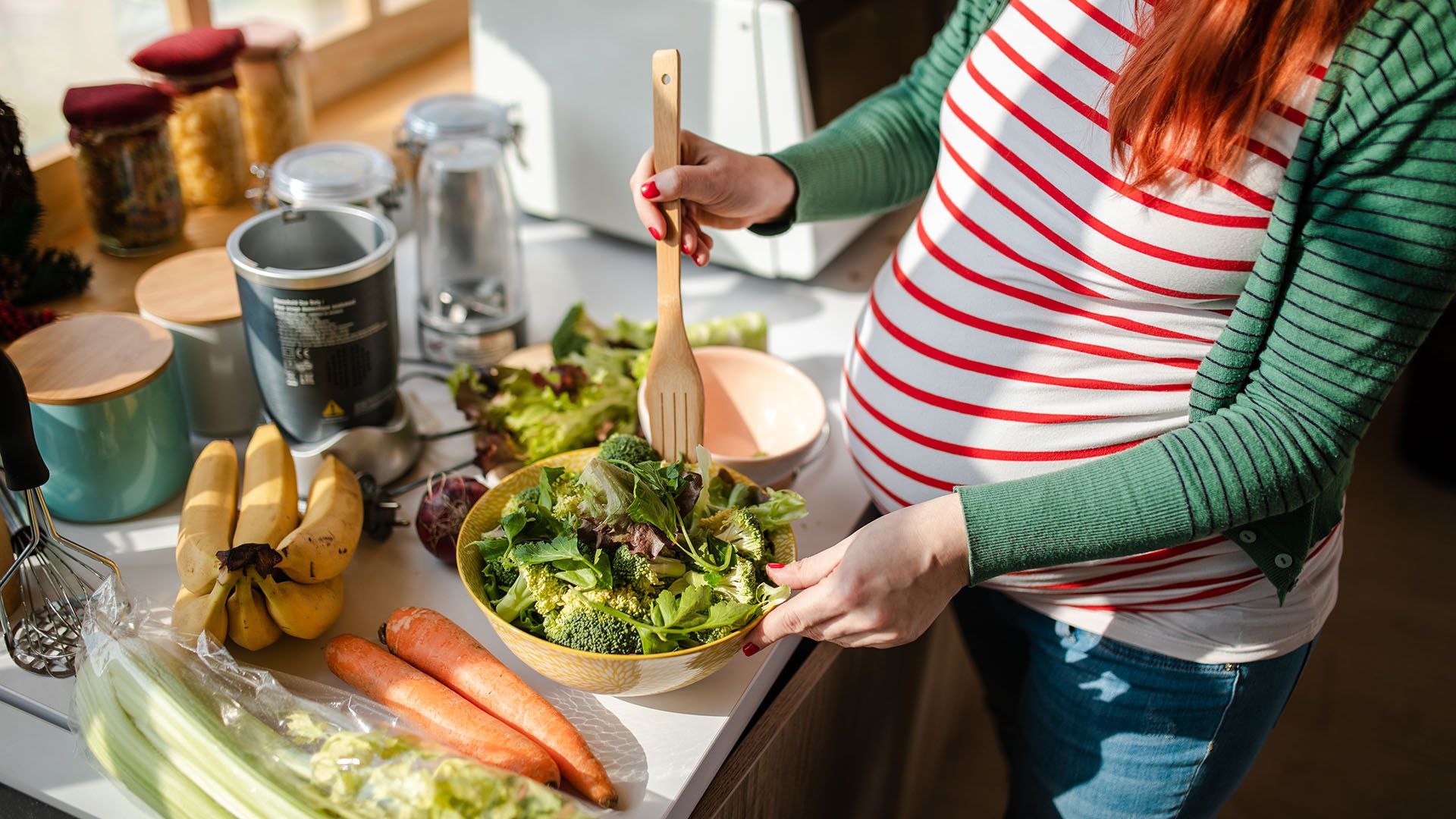 Gravid kvinne som lager salat til hverdagsmat.