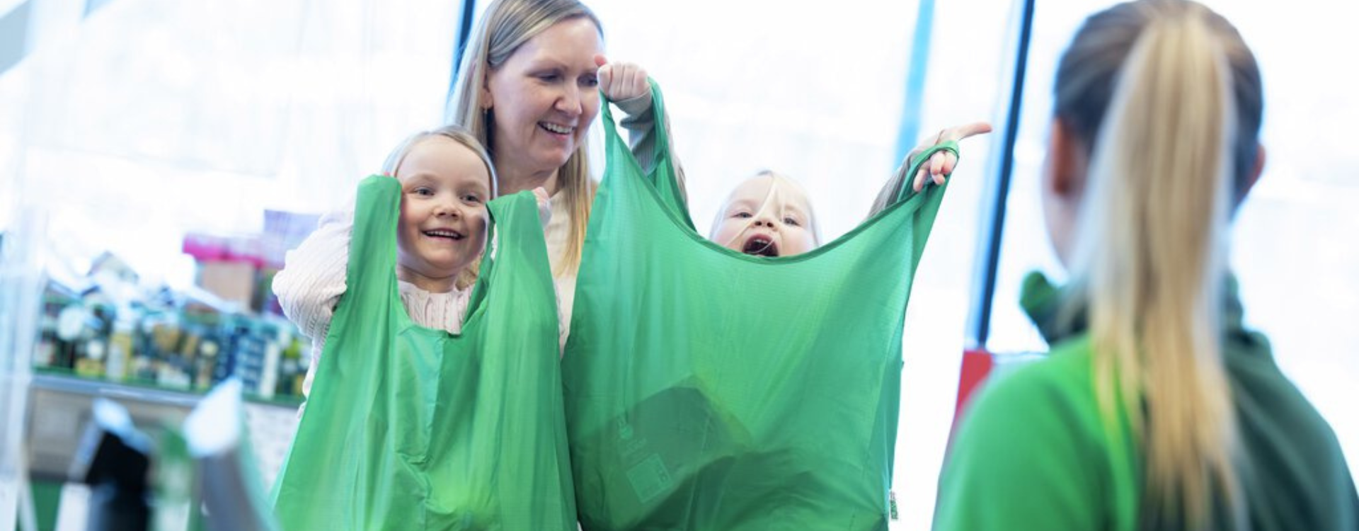 Kvinne i kassa på matbutikken med to barn.