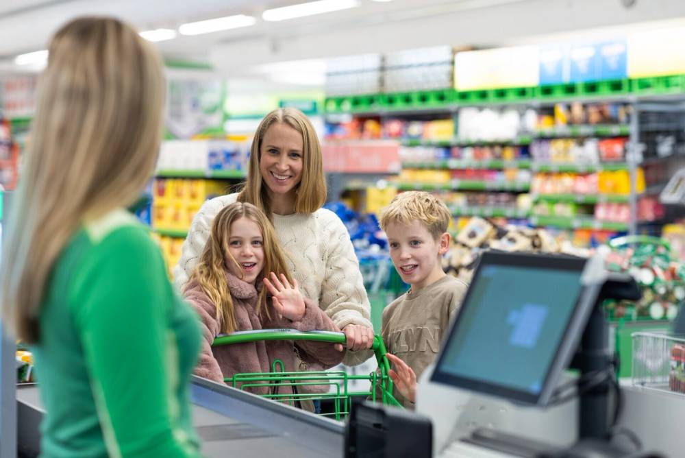 Kvinne med barn som skal betale i kassa på KIWI.