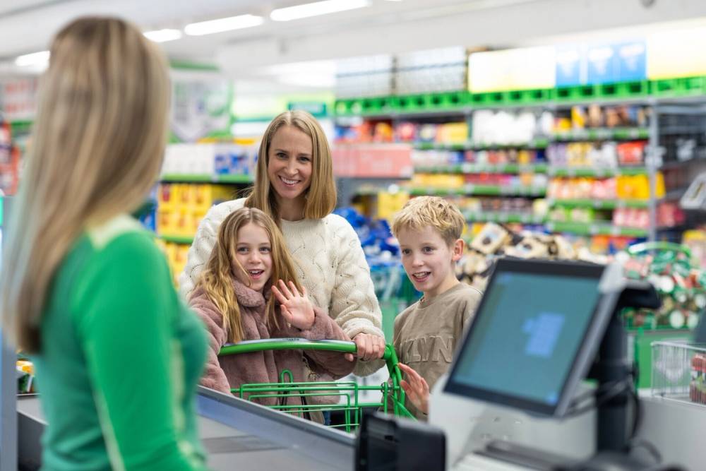 Kvinne med barn som skal betale i kassa på KIWI.