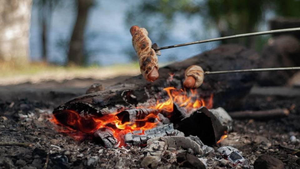 Pølser i pinnebrød som grilles på bål.