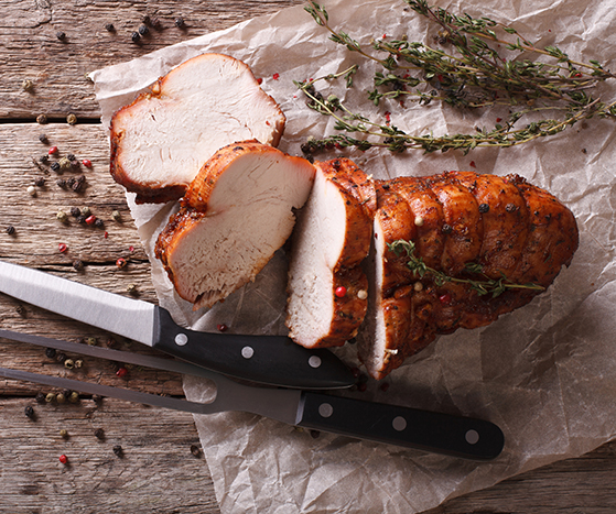 Delt kalkun med kniv og kjøttgaffel ved siden av.