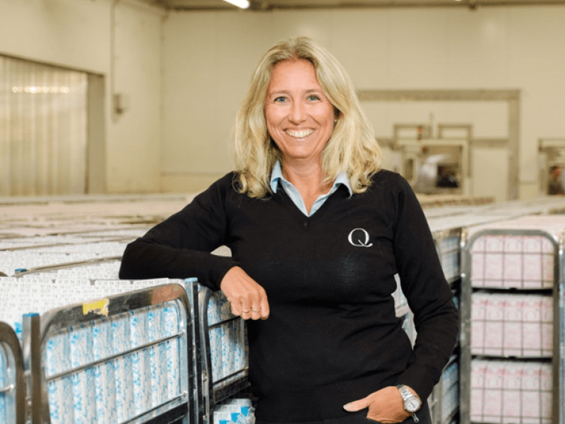 Portrett av Kristine Aasheim fra Q-Meieriene, lent mot melkekasser i et lager.