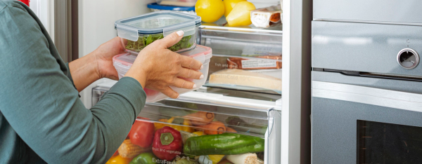 En som pakker inn frukt og grønt i kjøleskapet for bedre holdbarhet.