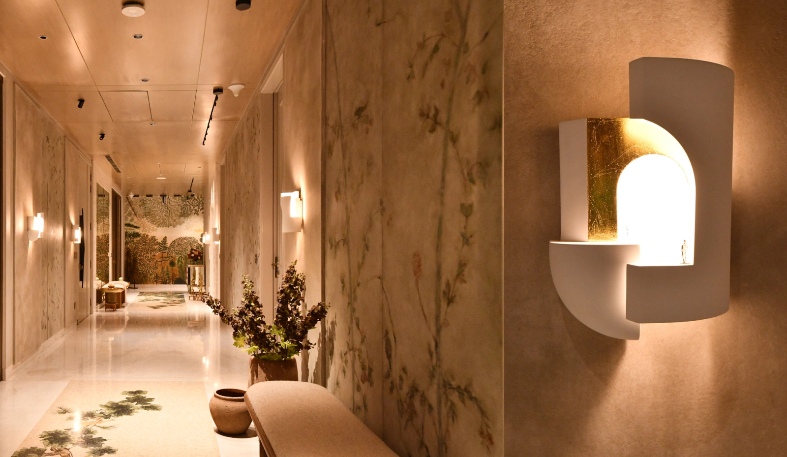 A luxurious, marble-clad corridor with warm ambient lighting and sculptural wall sconces creates an elegant, boutique-hotel-inspired ambiance.