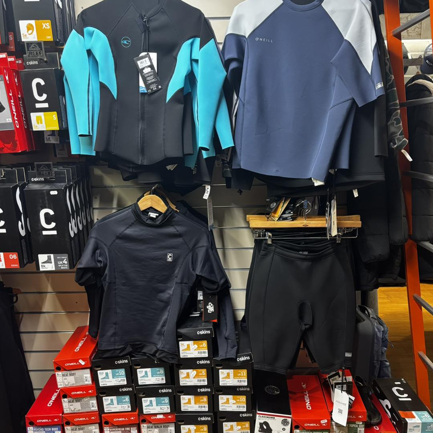 Wetsuit tops on the shelf in our shop