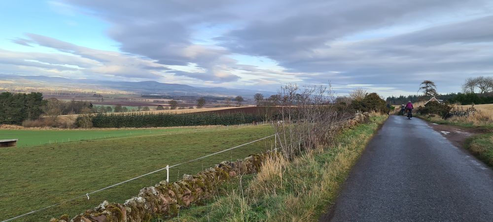 a photo showing a cyclist on a small road with views to the left of Strathmore Valley