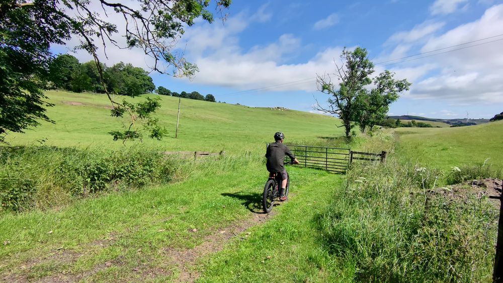 A cyclist approaches a gate on a grassy track