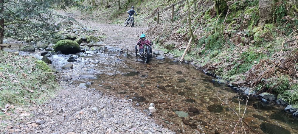 photo of an adpative rider trying to cross a deep river crossing on a gravel trail