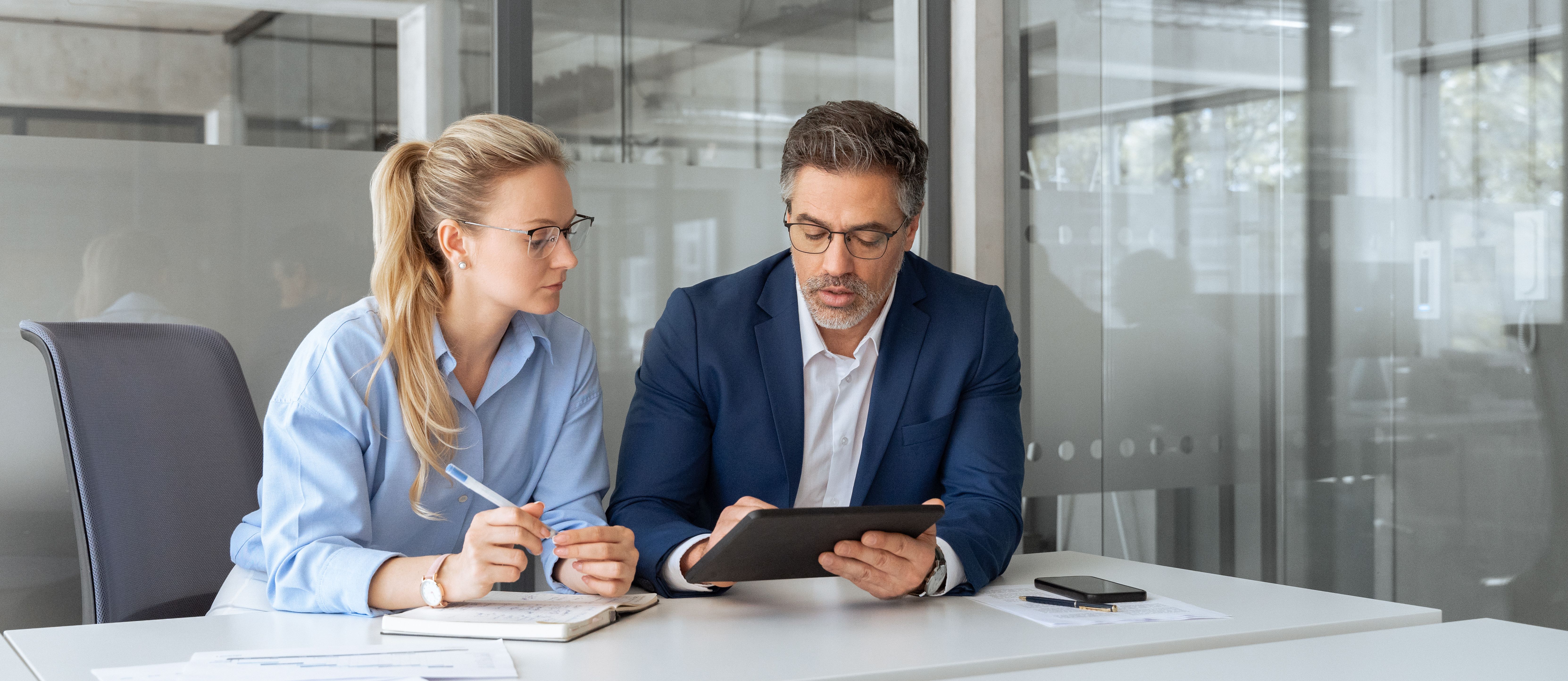 Female and male office managers looking at tablet