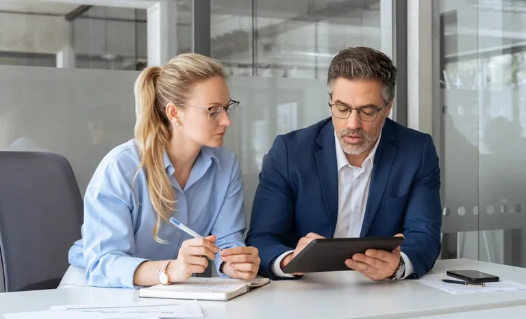 Female and male office managers looking at tablet