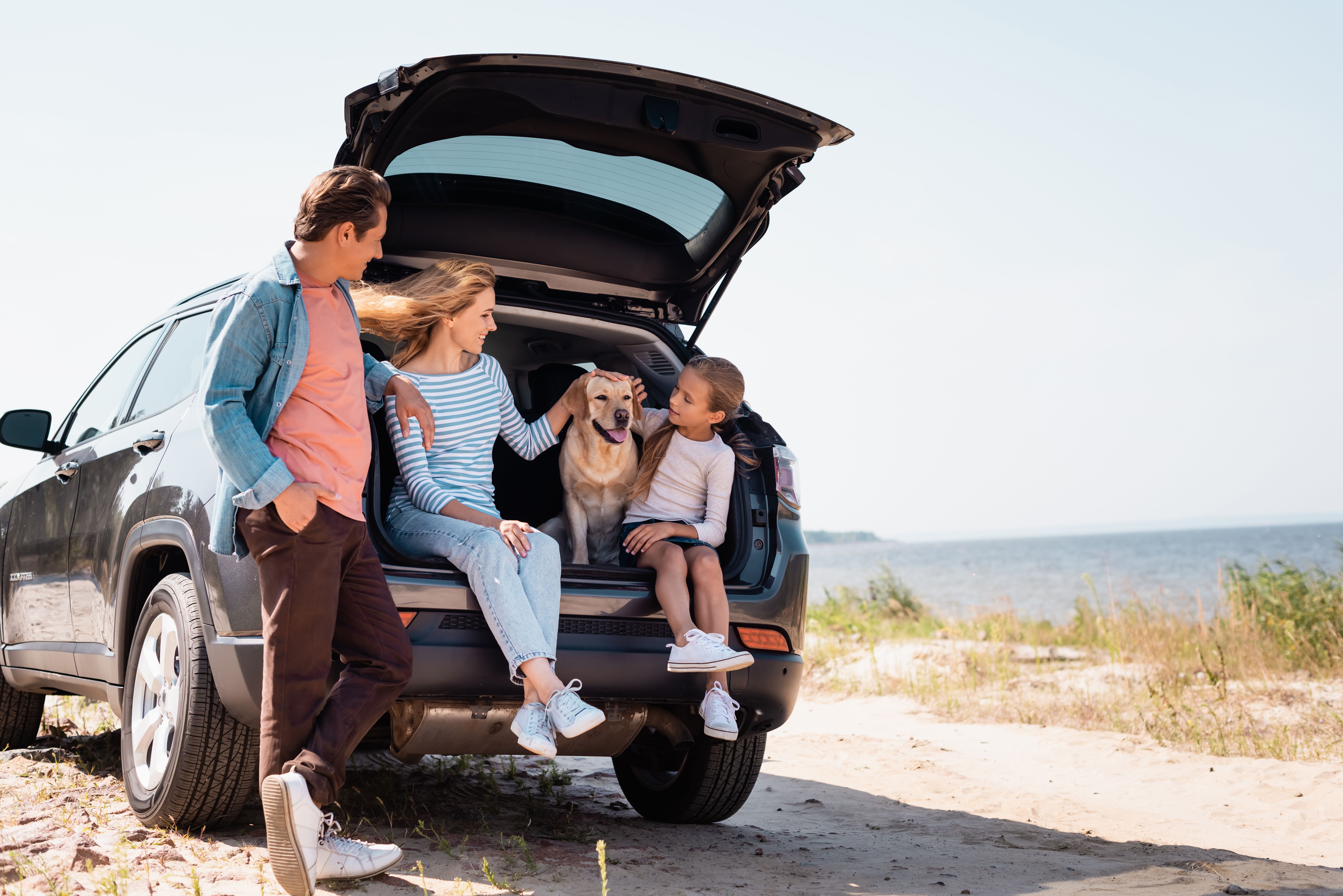 family with dog sitting in the back of their open boar car