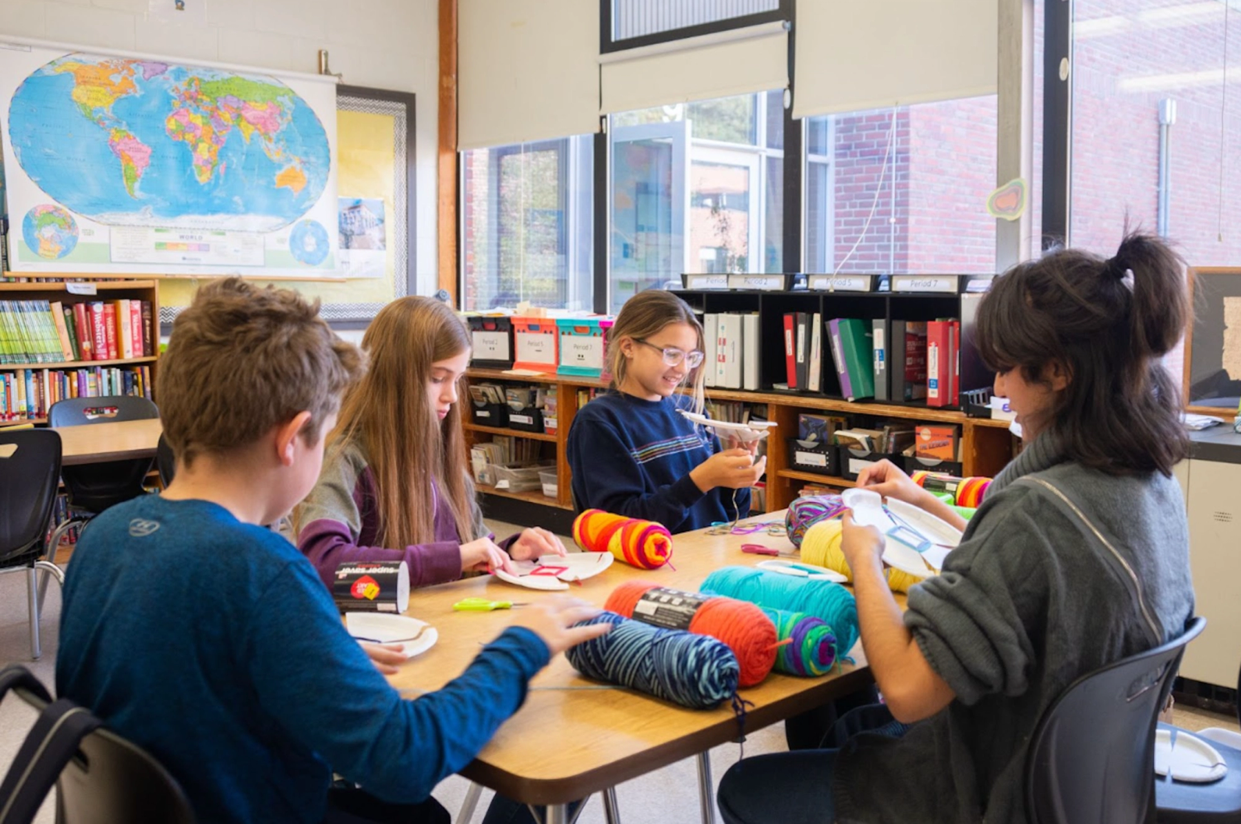 MAT student teaching children to make art with yarn.