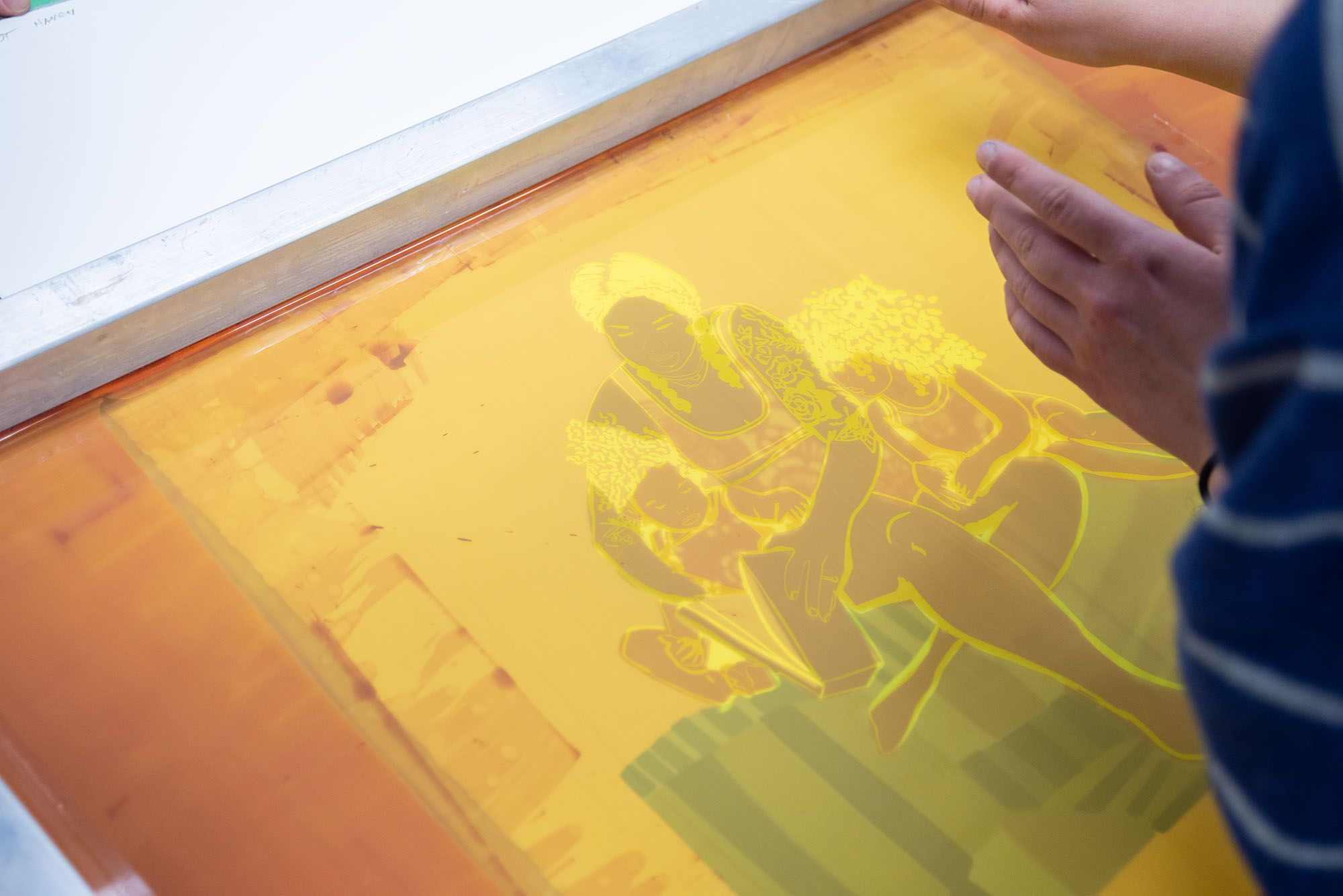 An exposed silkscreen with an illustration of a mother reading to her two daughters.