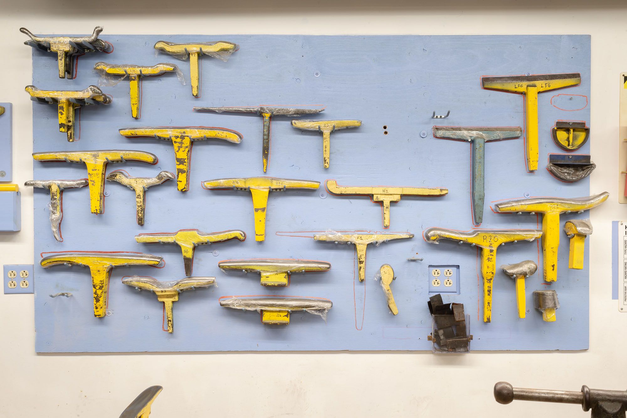 A blue pegboard full of yellow tools.