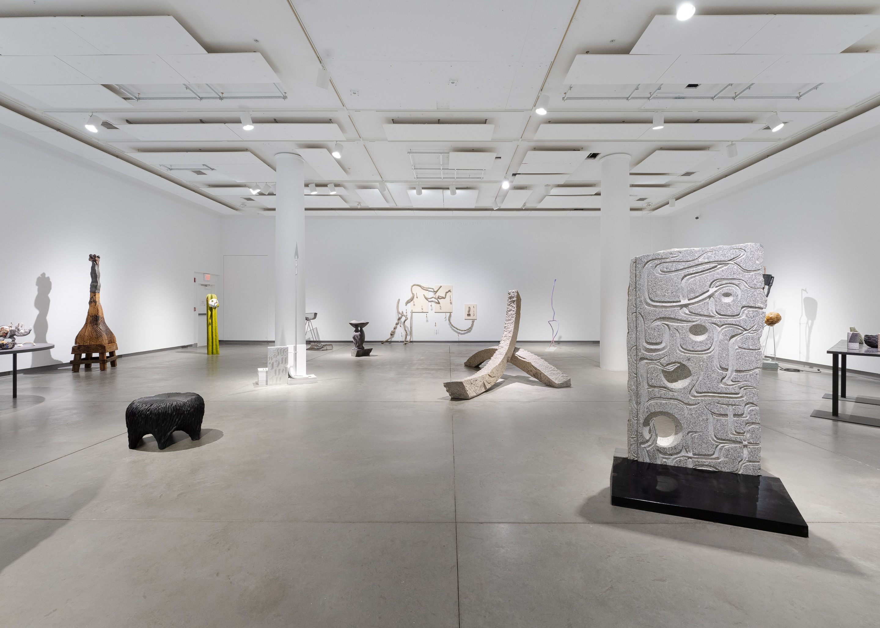 Installation view of a carved stone sculpture in front of several other sculptures.