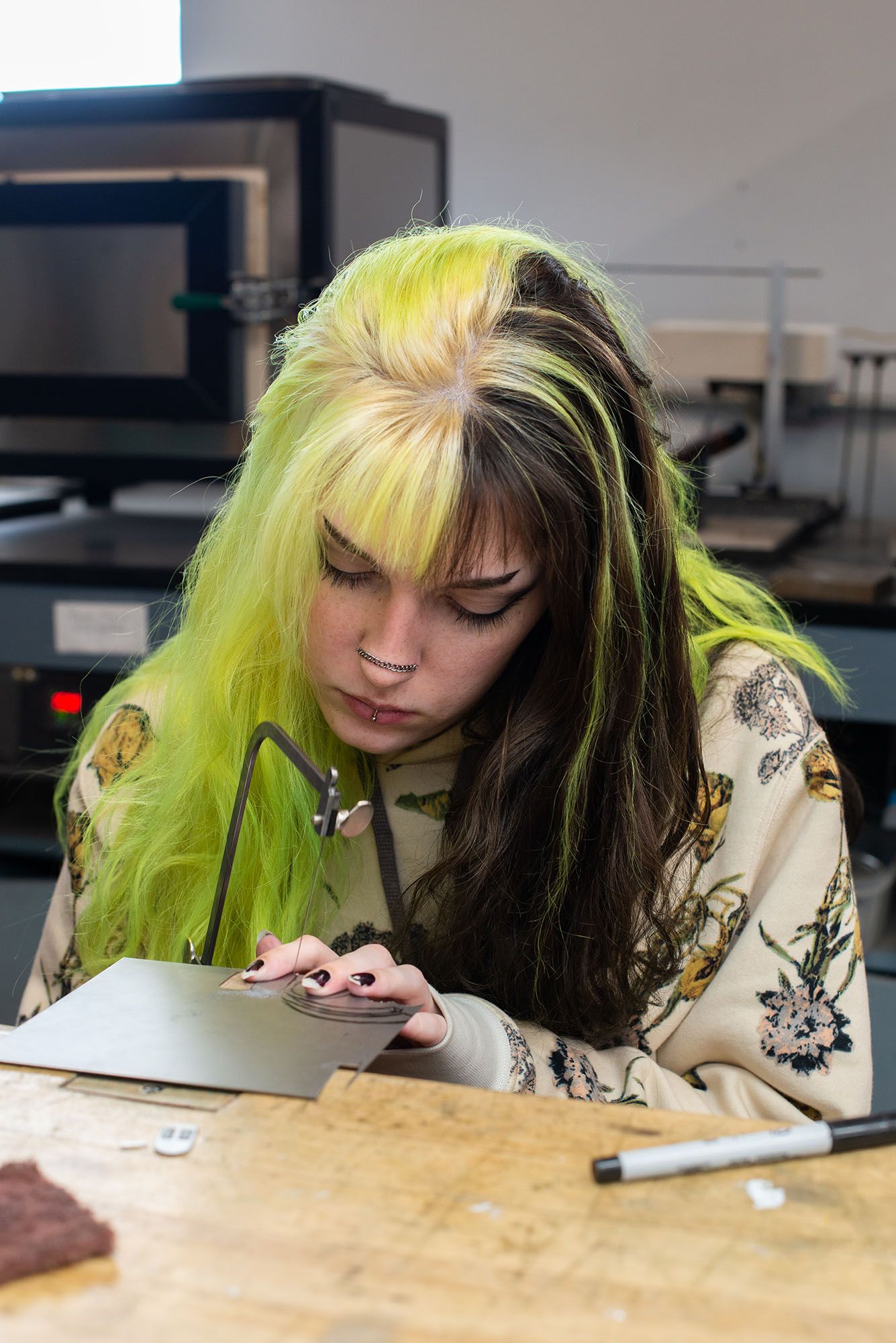 A student using a saw on a sheet of metal.