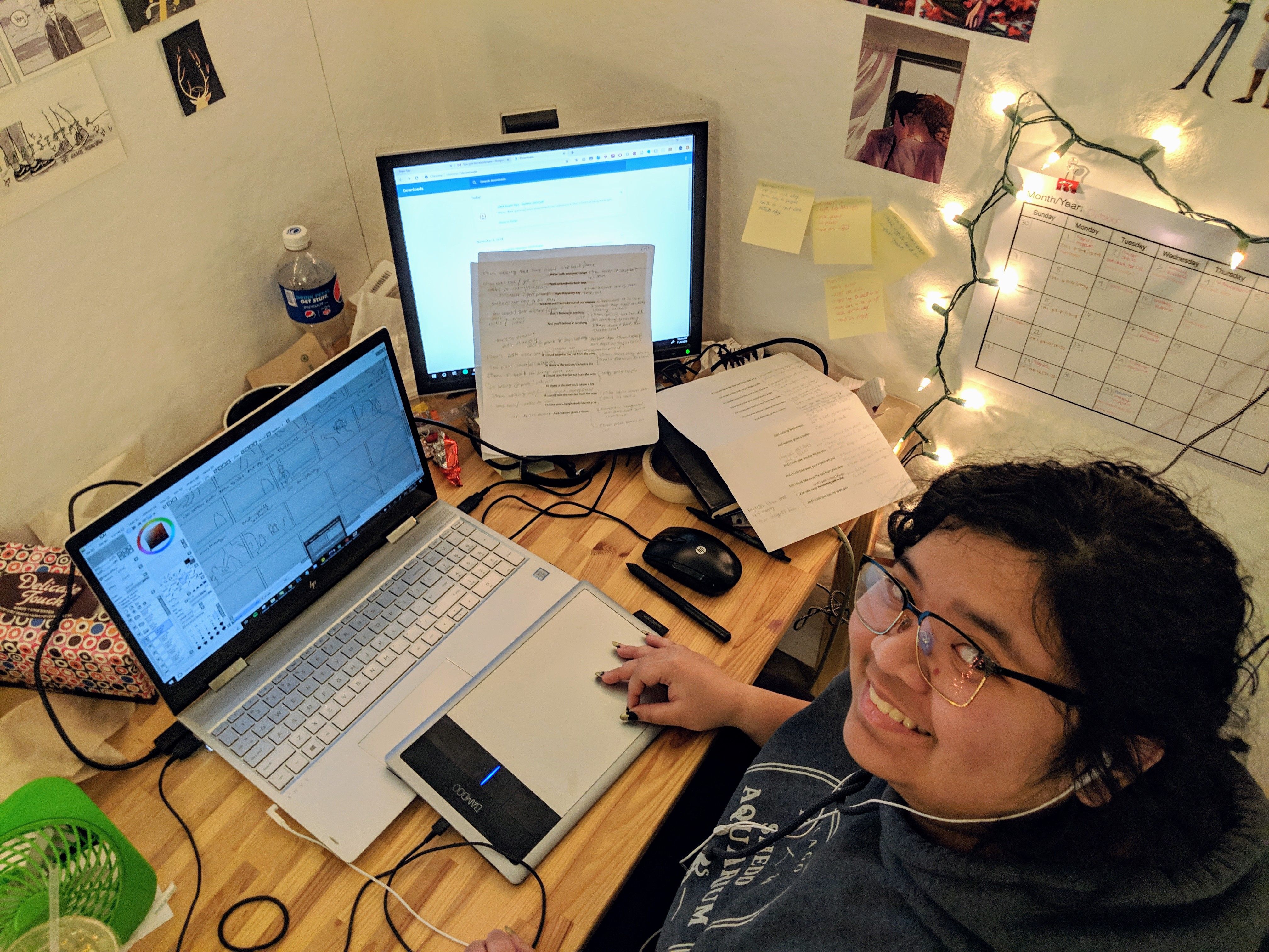 A student smiling in while building storyboards using their tablet in their studio space.