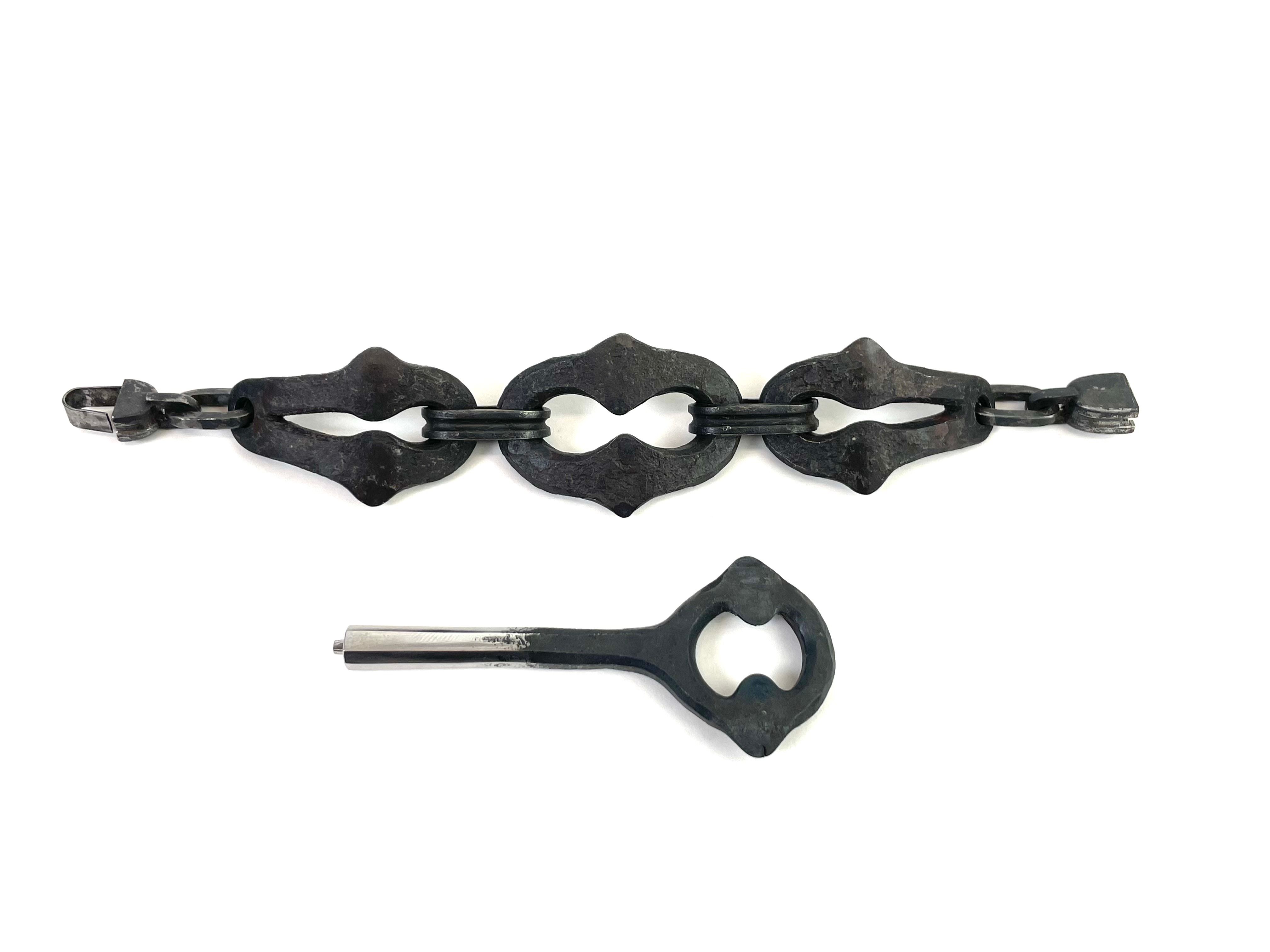 A three link iron chain bracelet with a key.