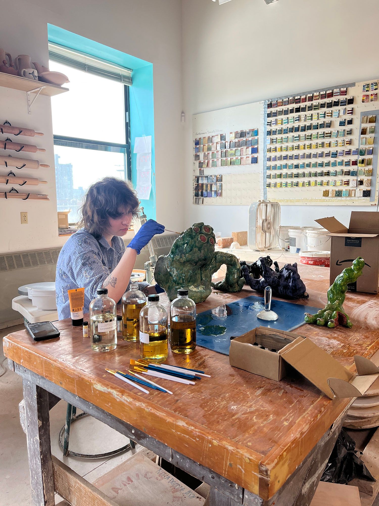 A student painting a lumpy alien-inspired sculpture.