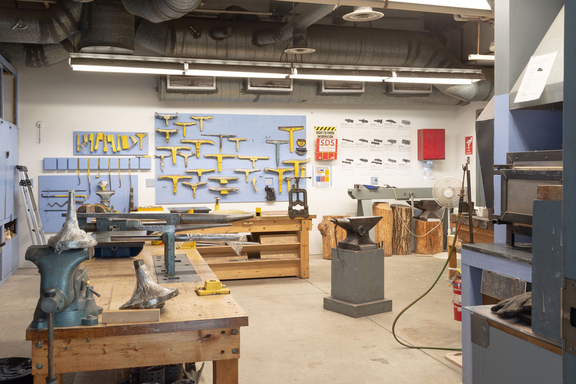 View of the Metalsmithing & Jewelry studio showing a wall full of tools, a workbench with clamps, and an anvil.