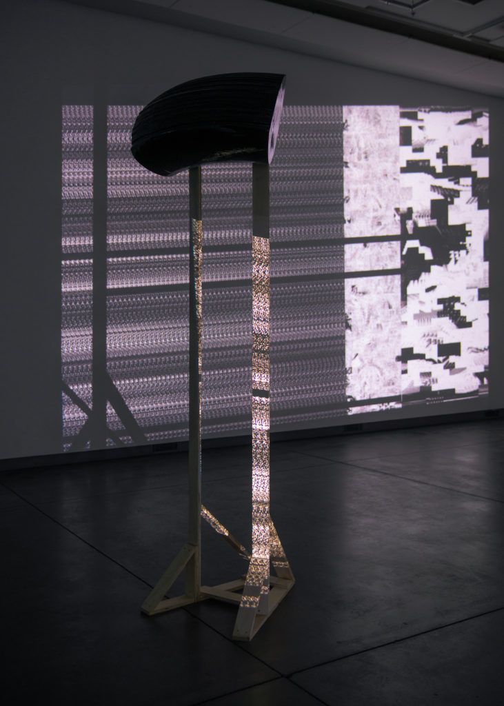 Gallery view of a sculptural structure and a projection of a repeating pattern.