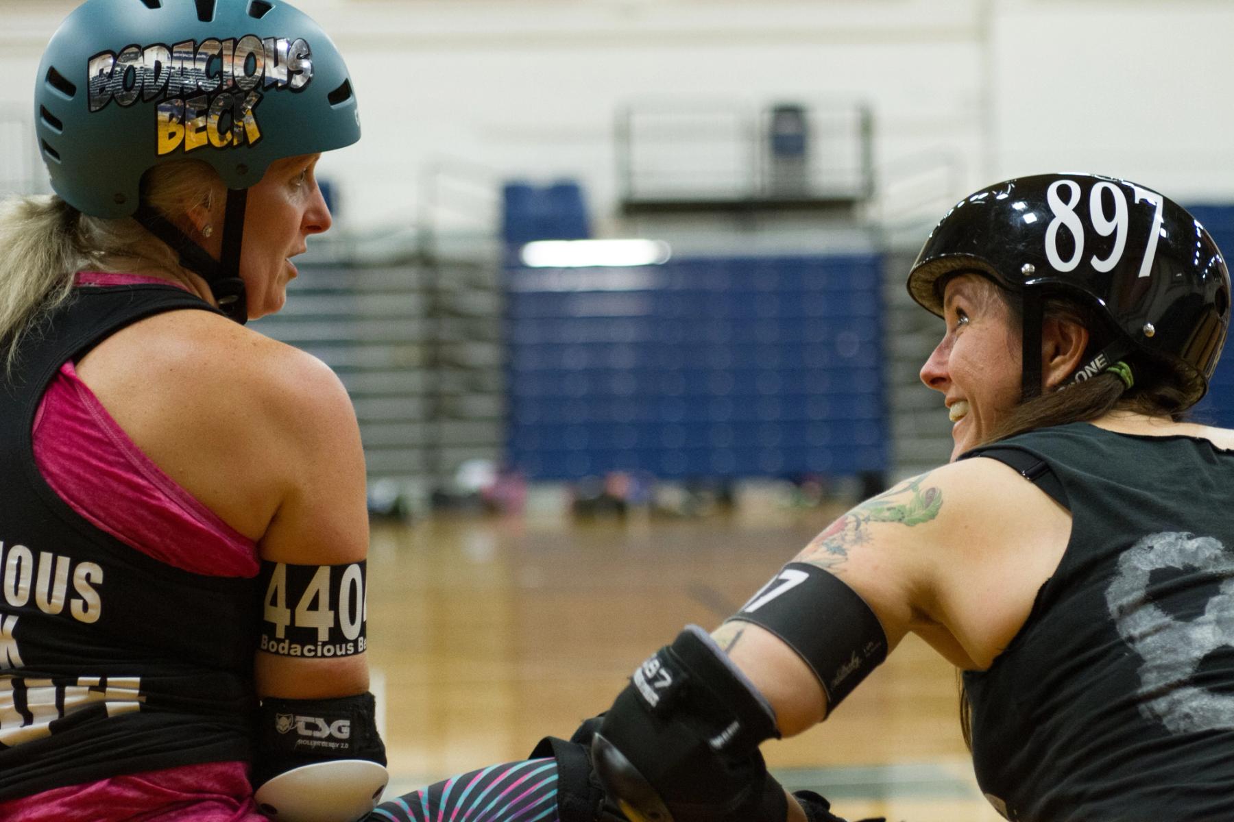 Two women talking to each other, preparing for a roller derby game.