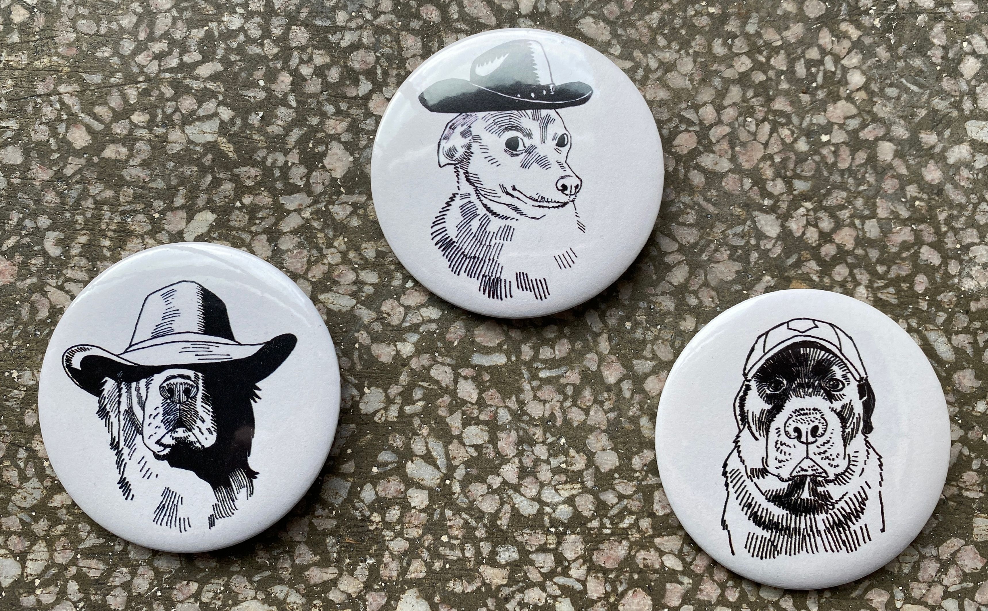 Three buttons with illustrations of dogs wearing hats.