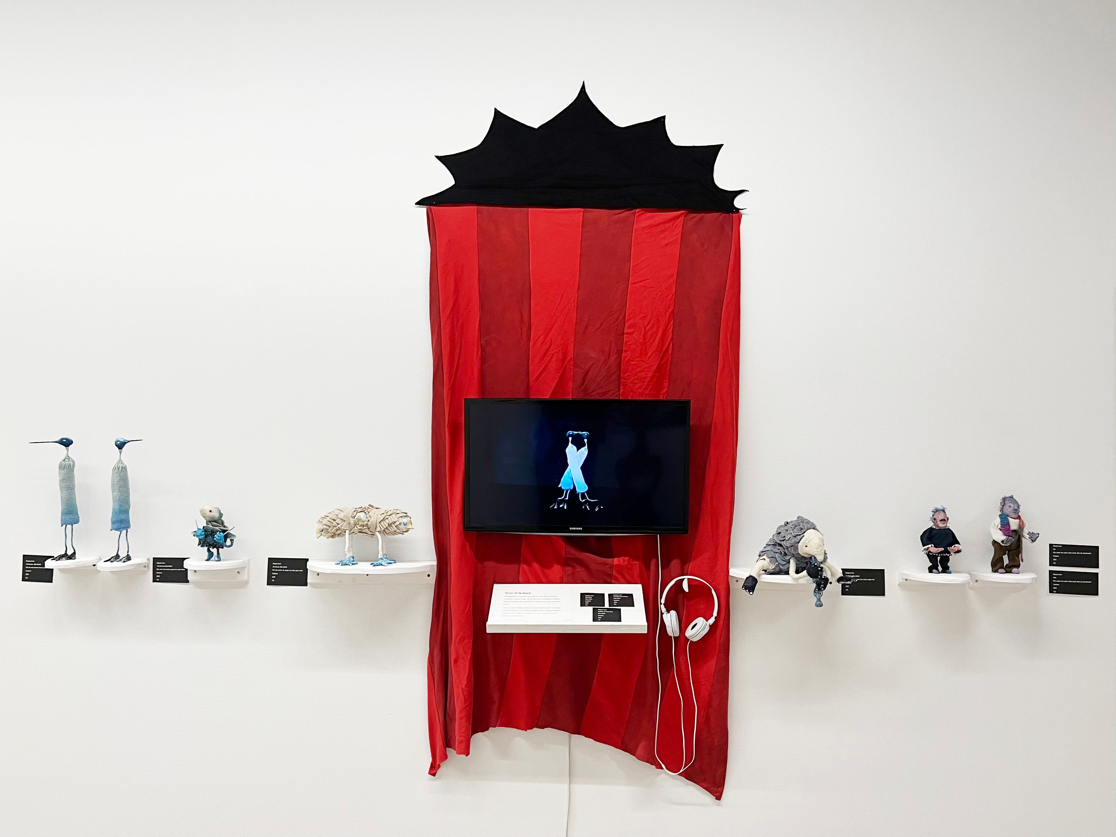 An installation of a stop-motion animation with sculptures displayed beside.