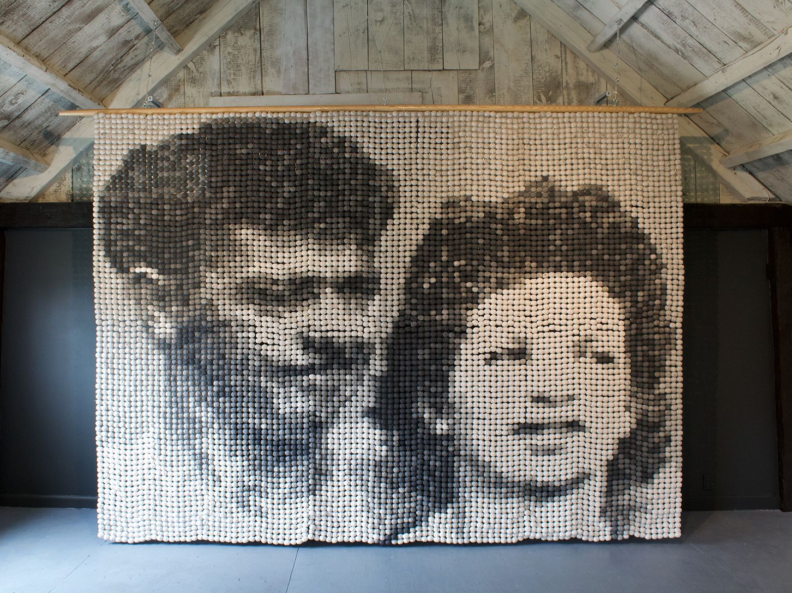 An installation of a hanging large beaded black an white portrait of a man and woman.