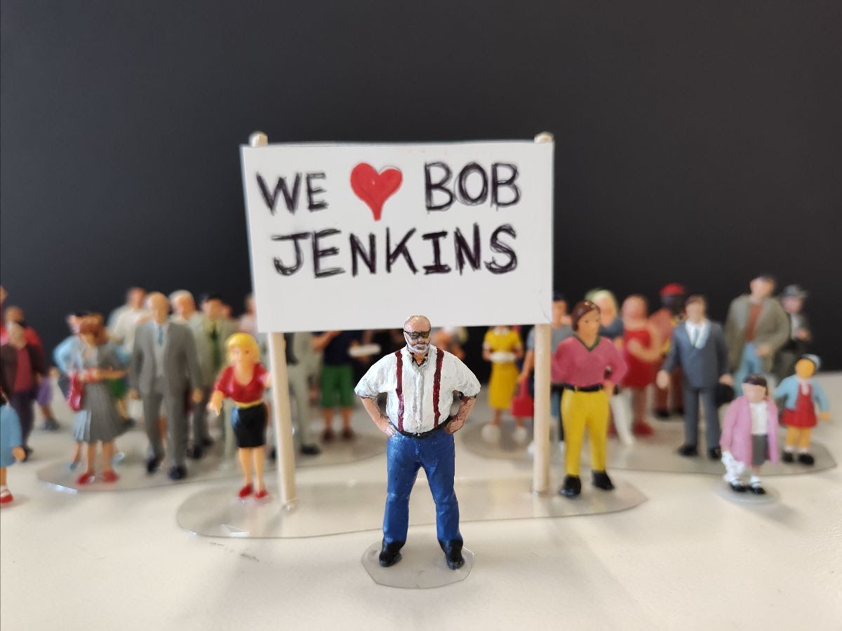 A group of miniature people with the sign that says, "We Heart Bob Jenkins"