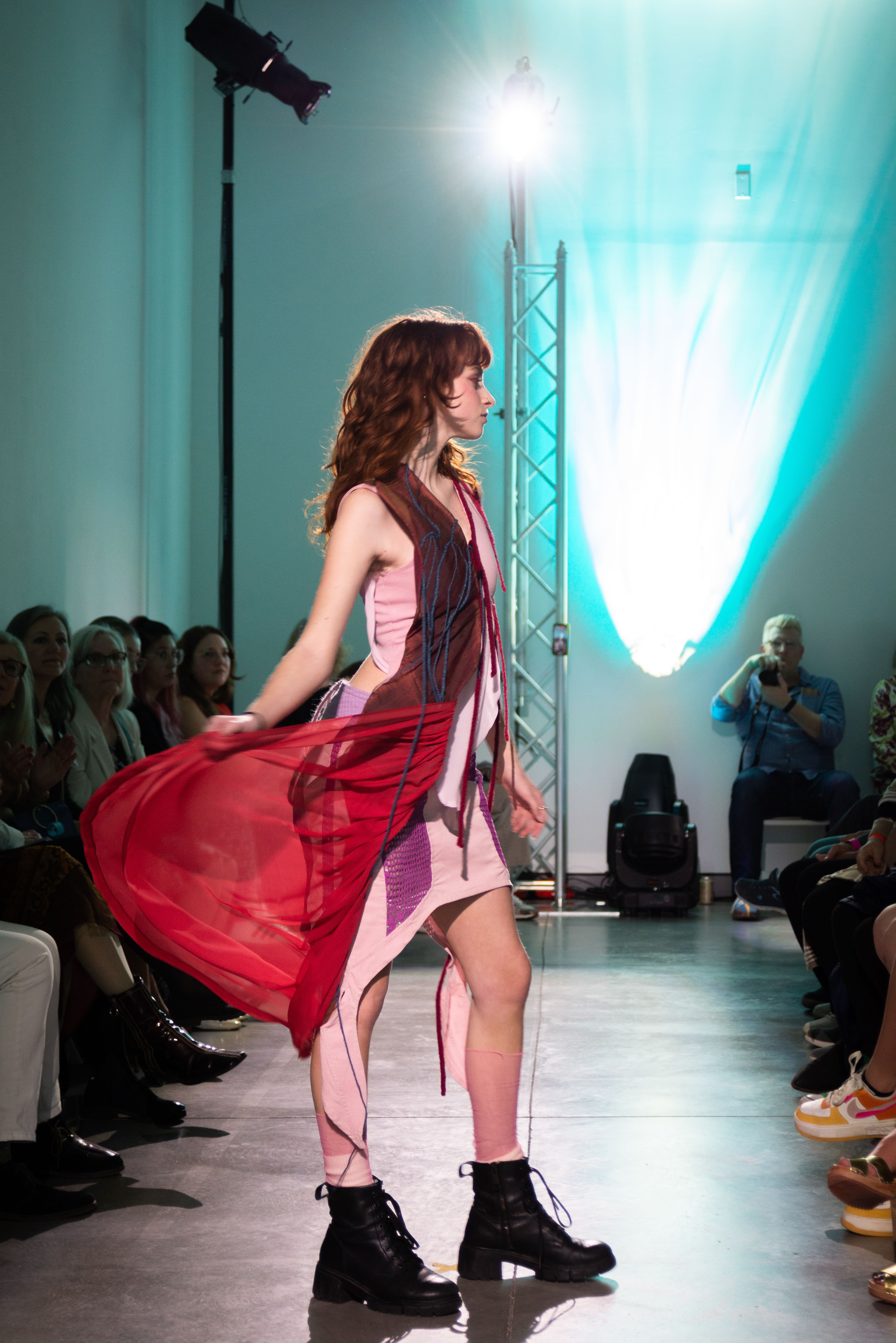 A model on the runway wearing an asymmetrical dress with dangling flesh-colored fabrics.