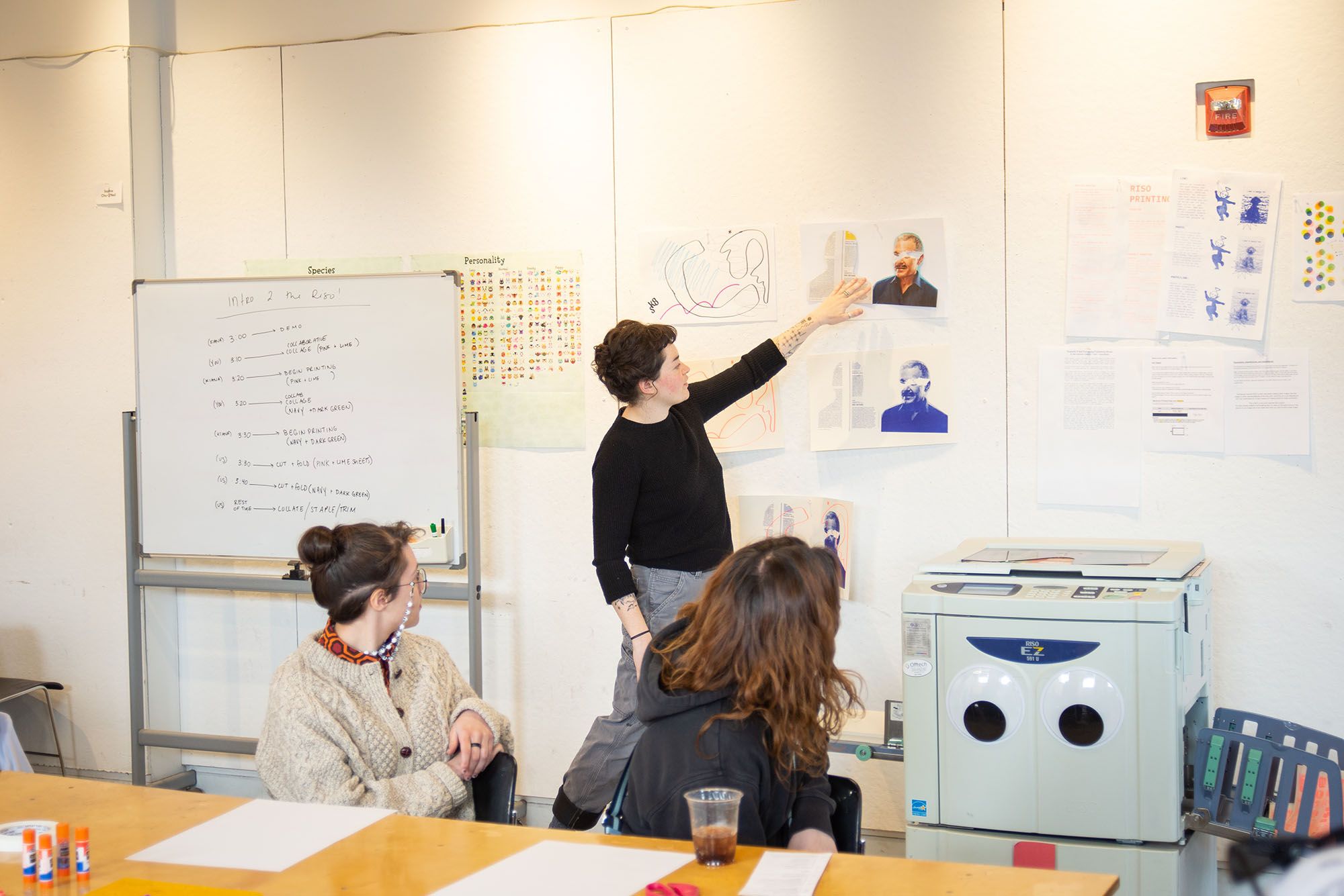 A professor pointing at an example collage during a risograph demo.