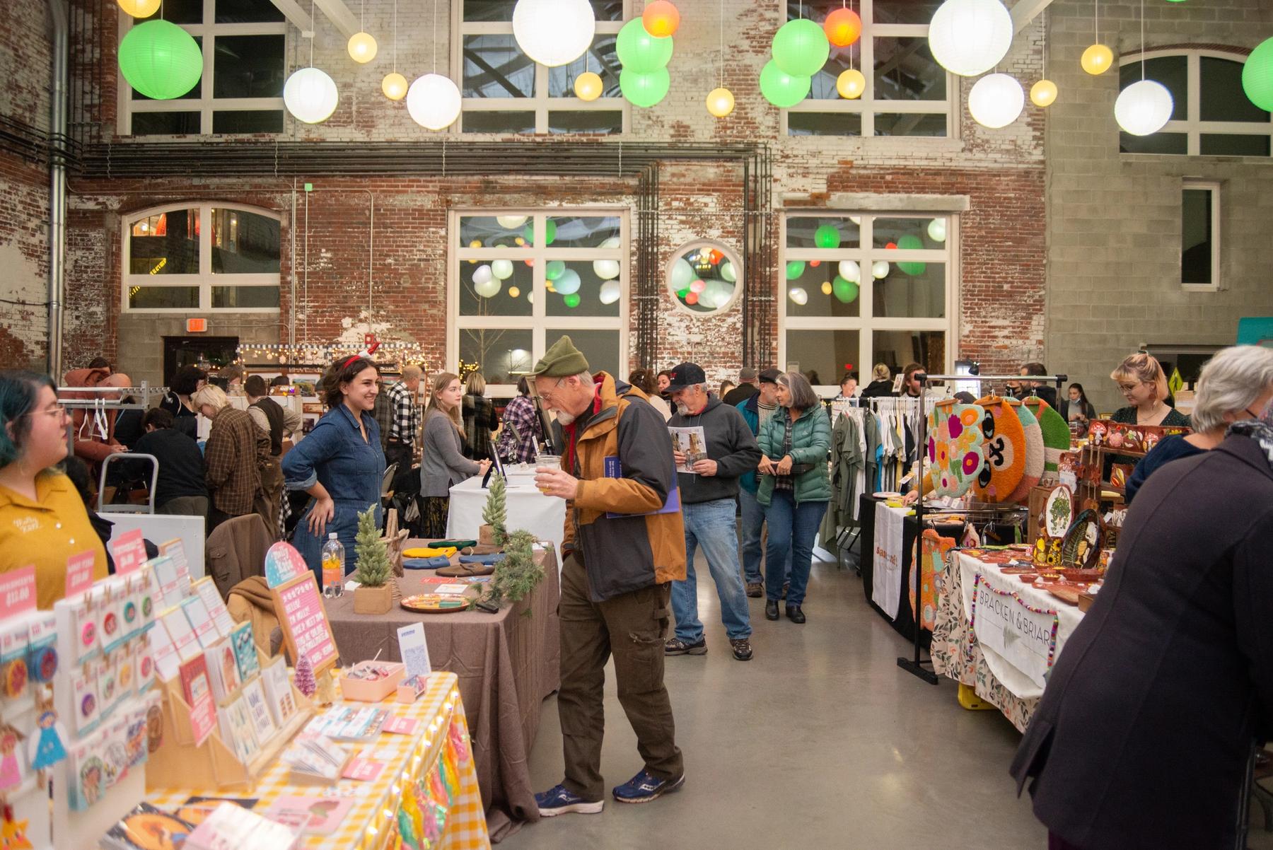 A crowd of shoppers looking between booths during a holiday sale.