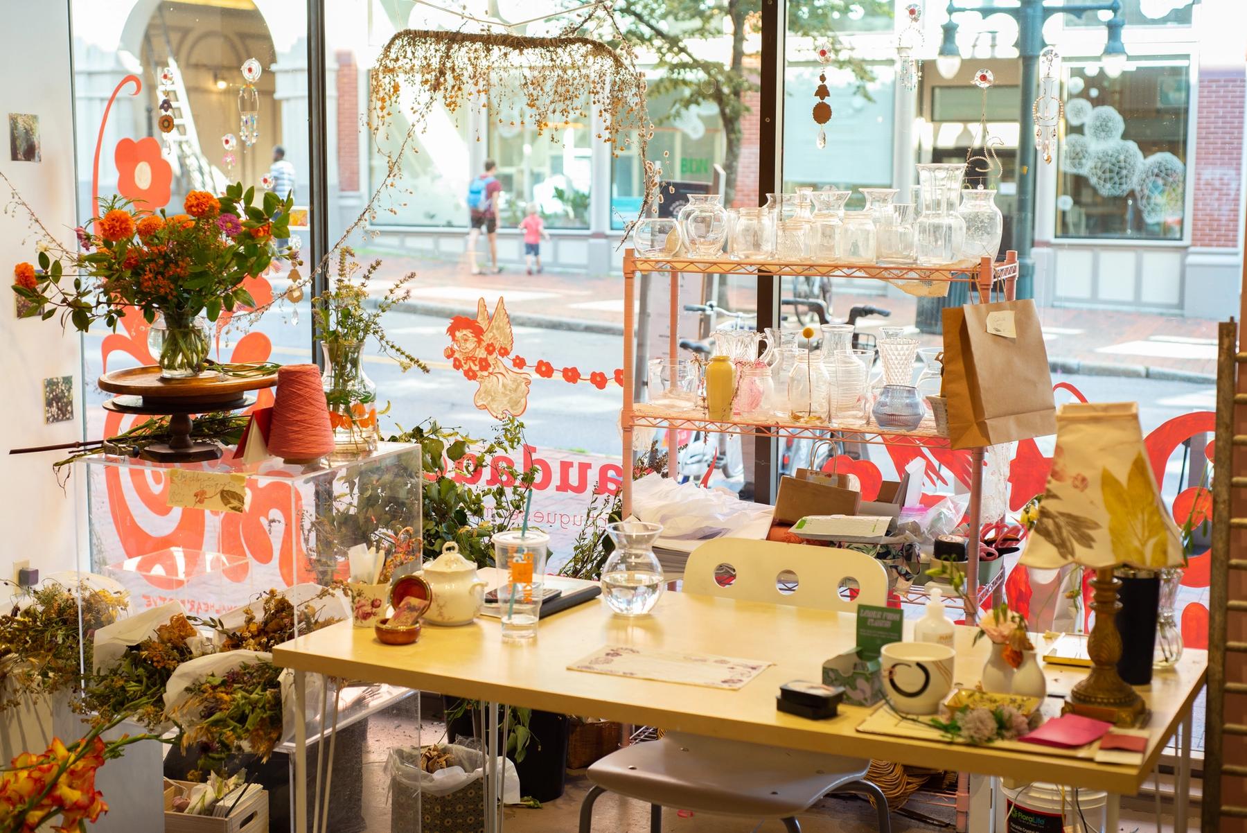 View of the Saudade pop-up shop windows with flowers and glass vases.
