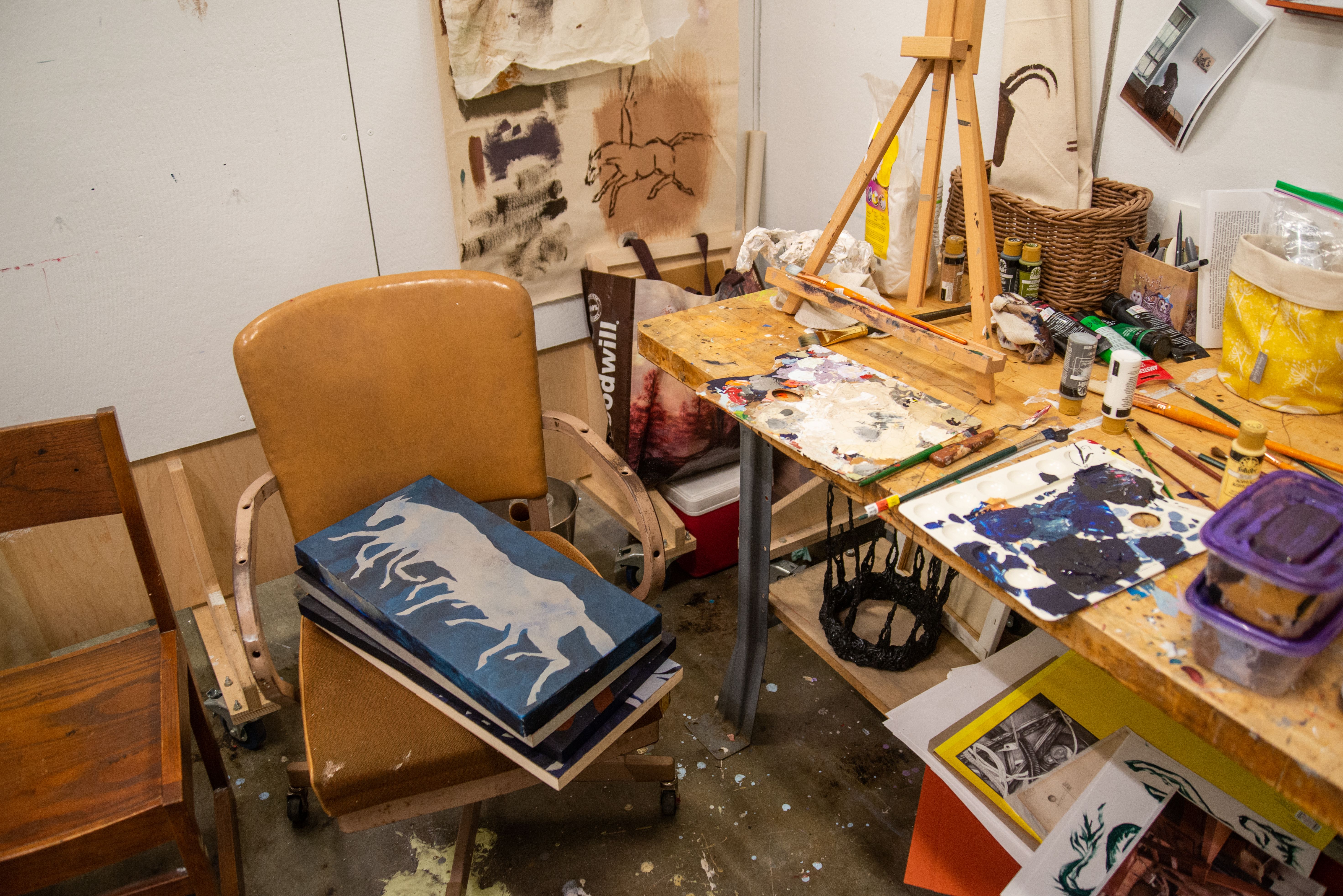 An MFA studio filled with paints, paintings, and other materials.