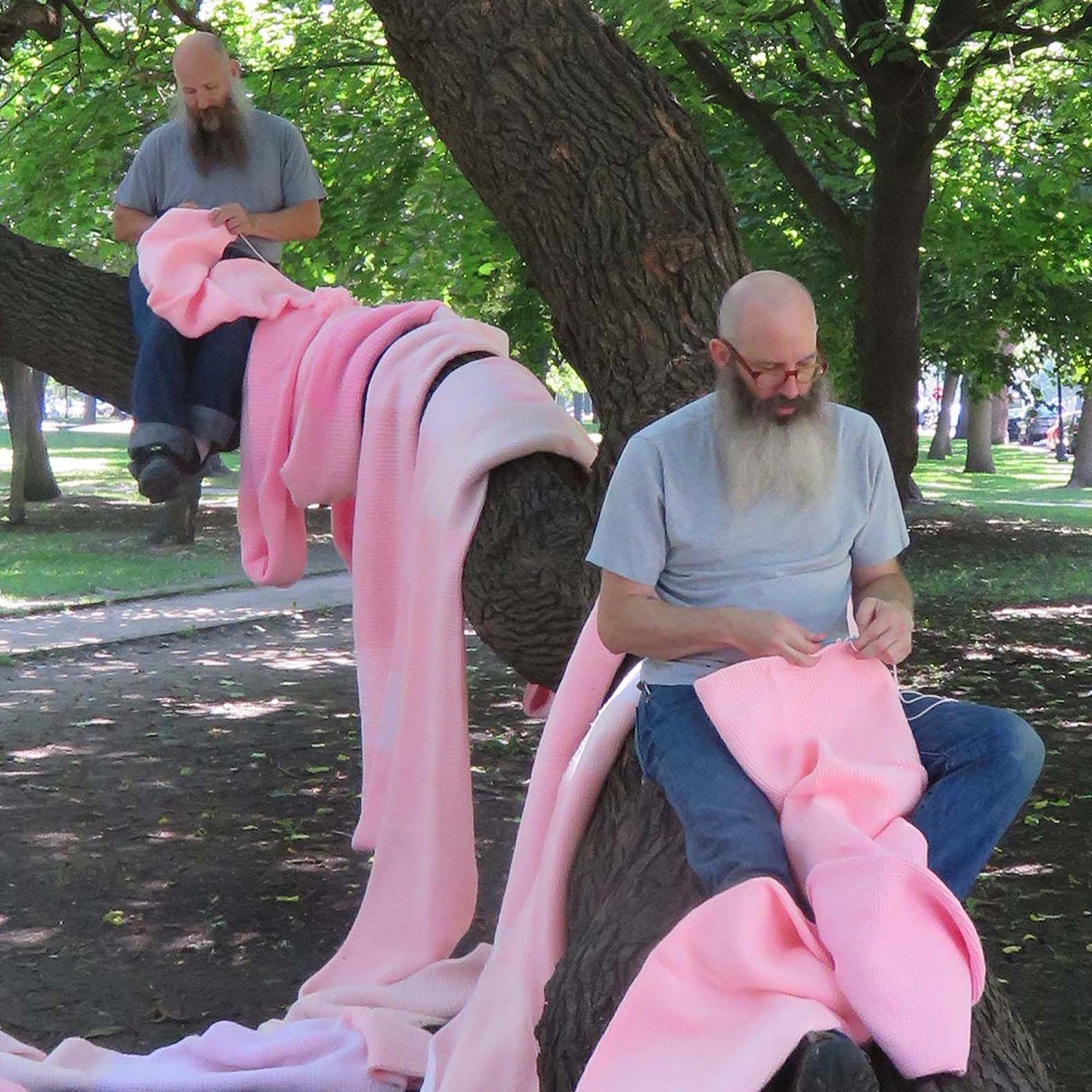 Miller and Shellabarger crocheting a pink tube while sitting in a tree.