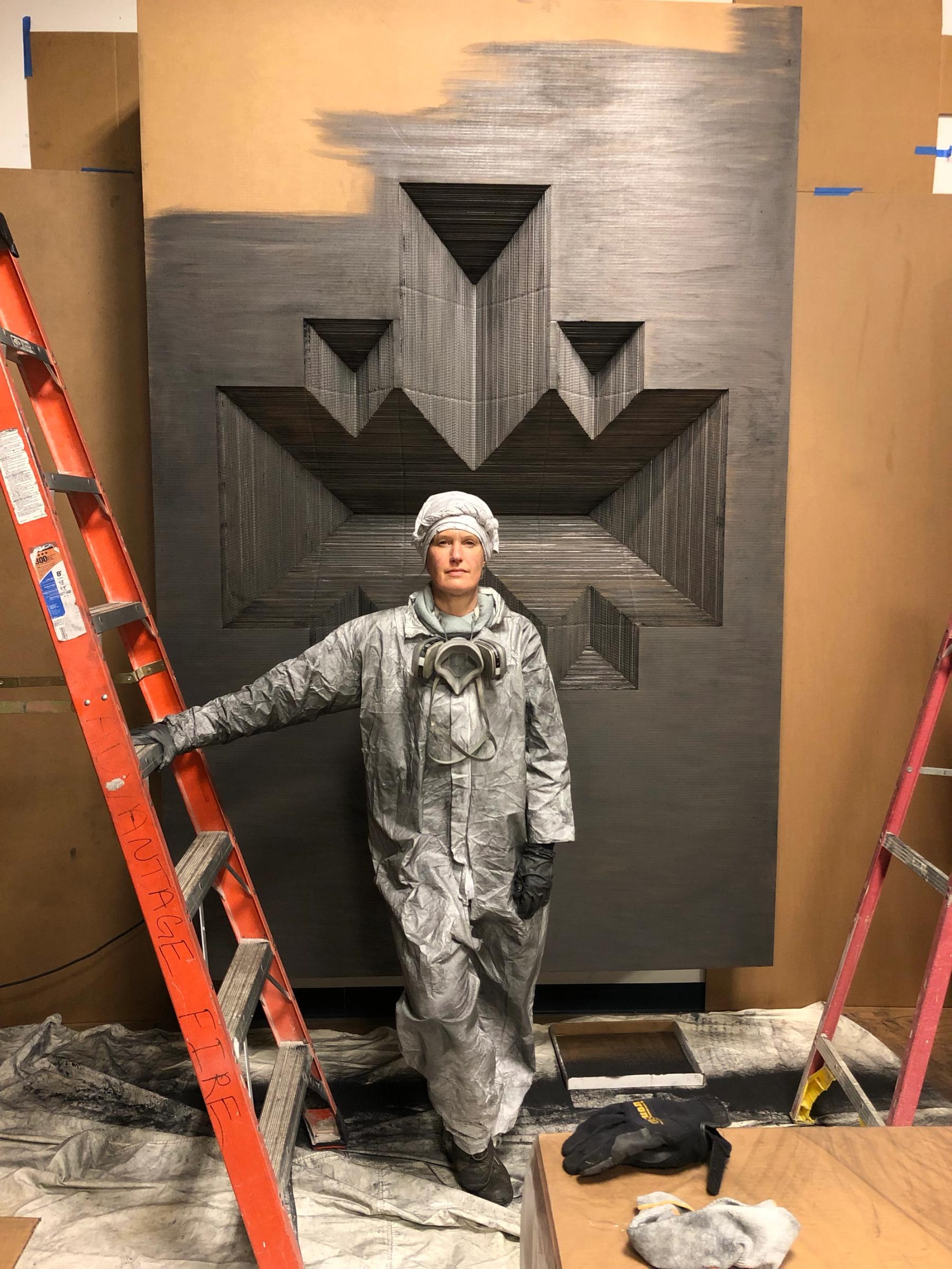 May Tveit standing in front of her sculpture with a ladder.