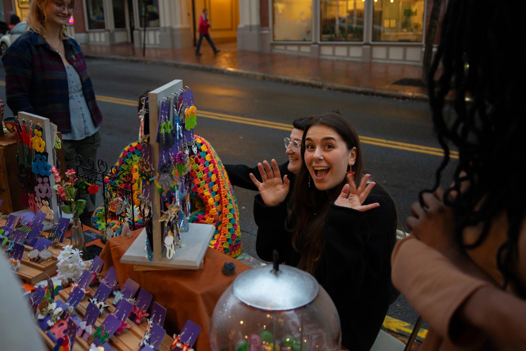 Two people selling chunky earrings during a First Friday Art Walk.