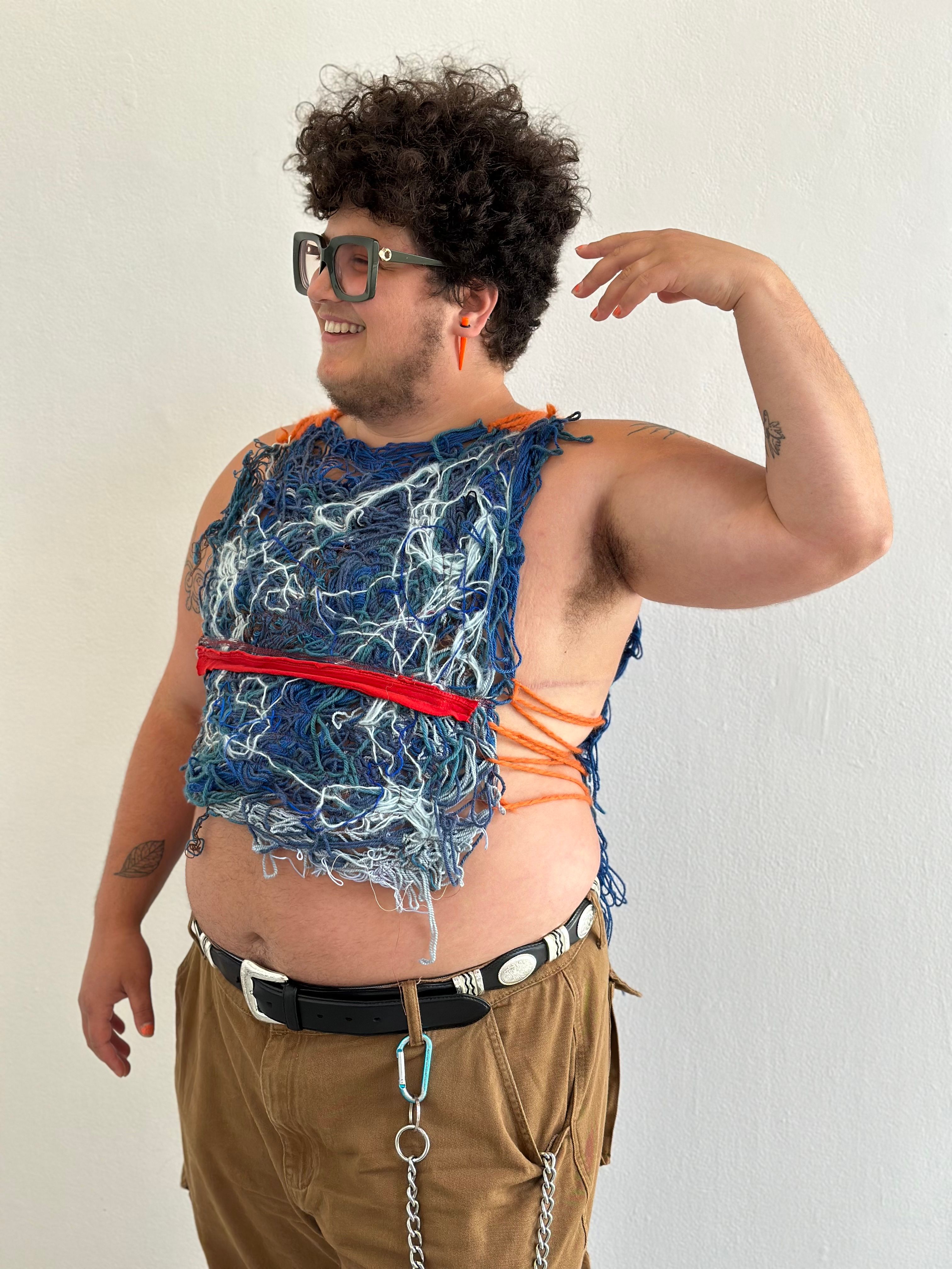 A model wearing a felted garment that emphasizes his top-surgery scars.