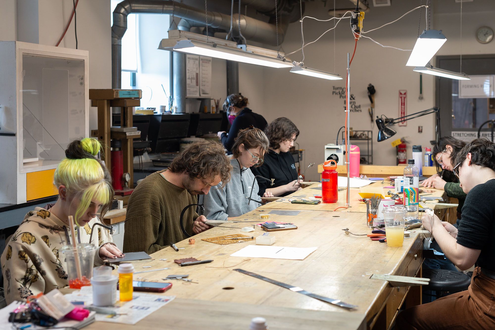 A class of students seated at a worktable, each focused on their own project.