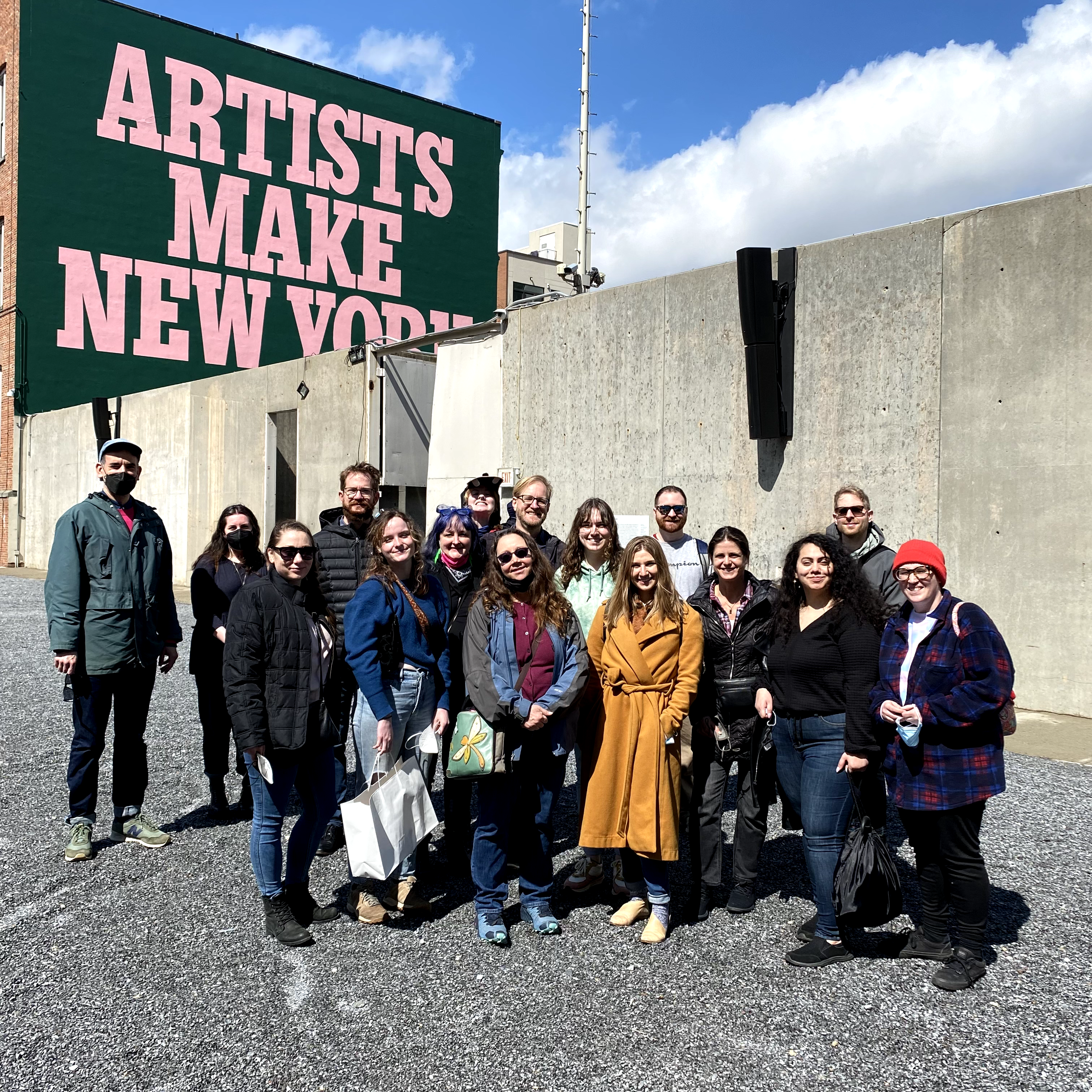 A group of MFA students posing in front of a sign that boldly reads "Artists make New York"