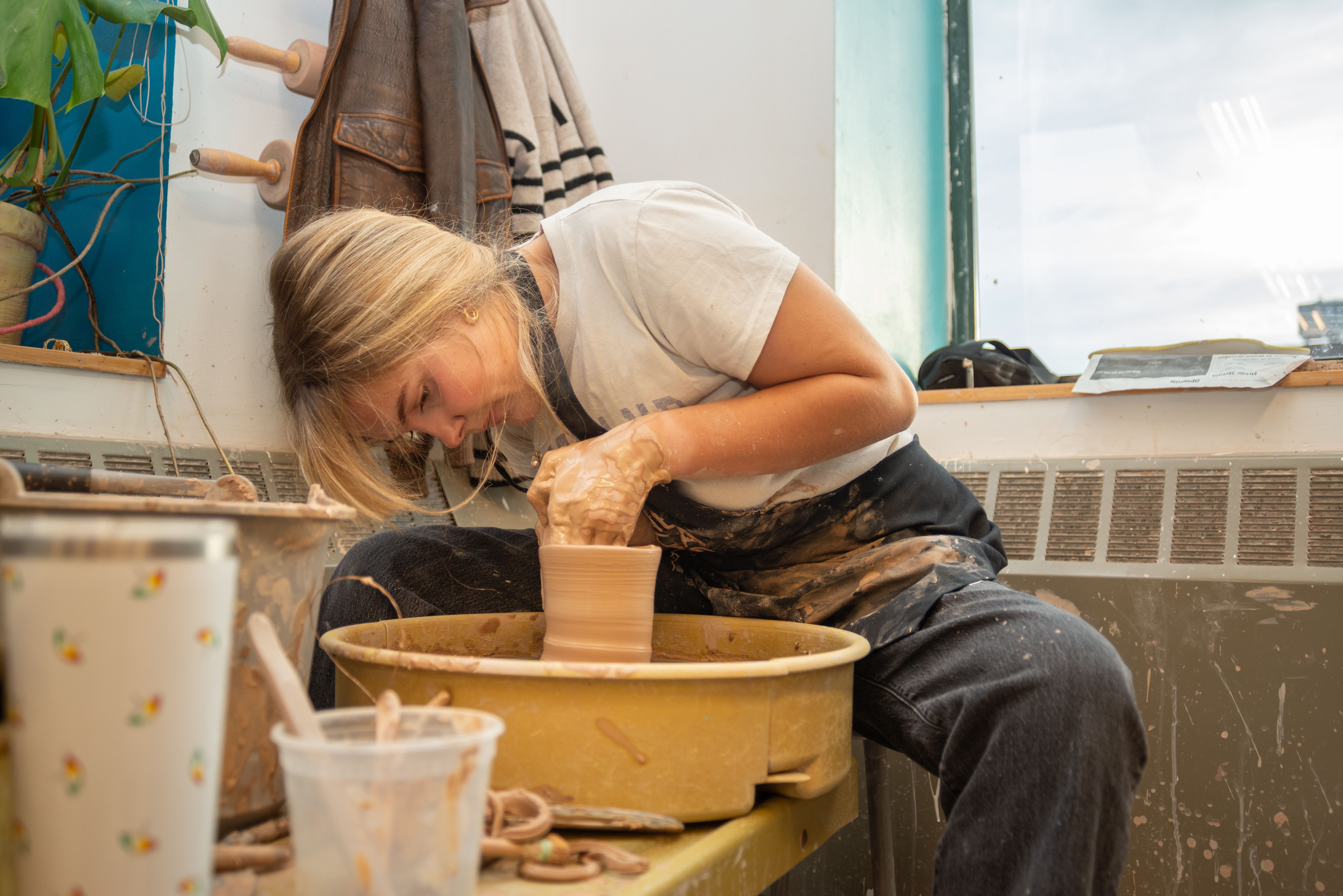 Student using a pottery wheel to make a vessel.