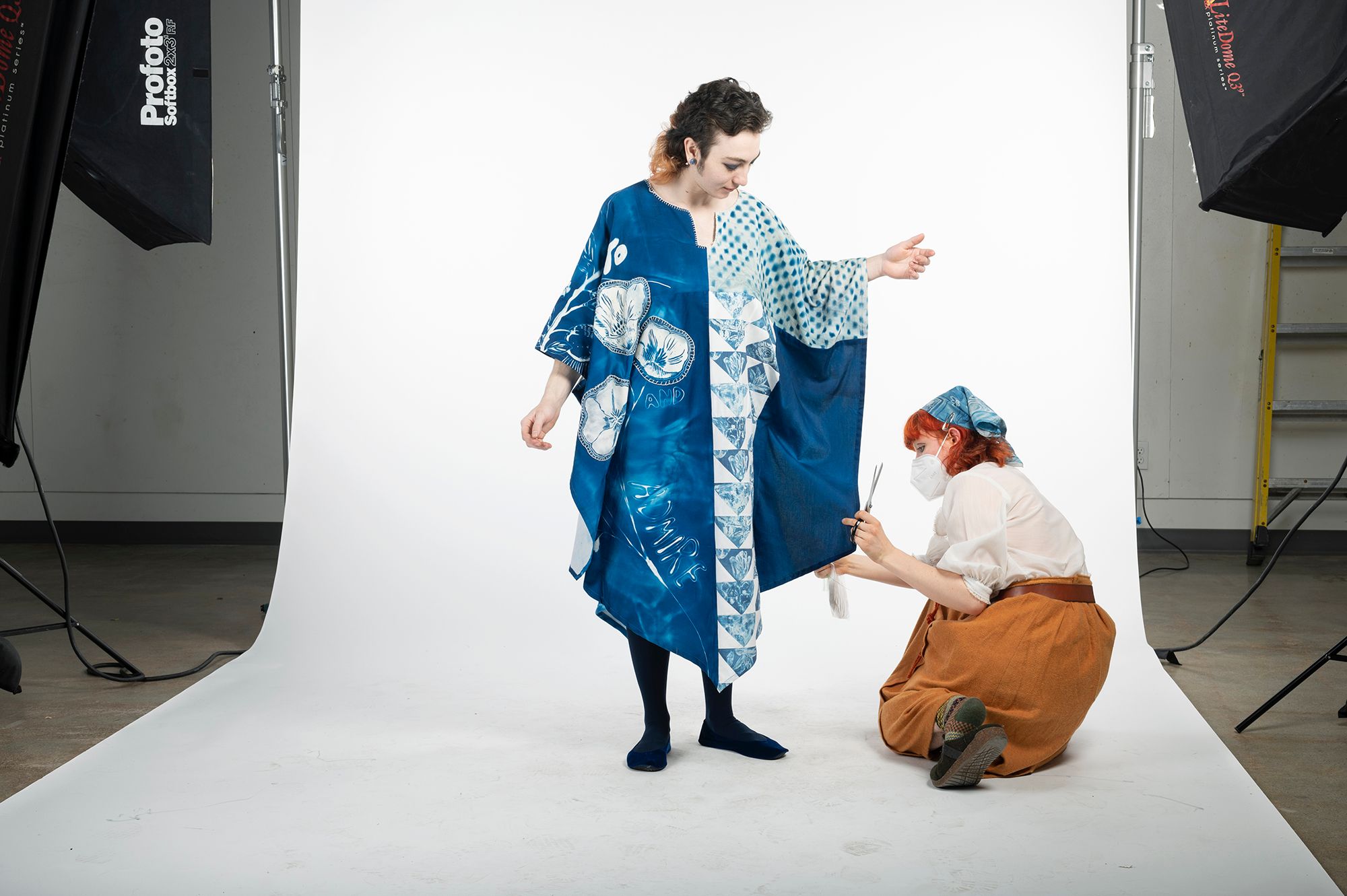 A student adjusting a blue garment on a model.